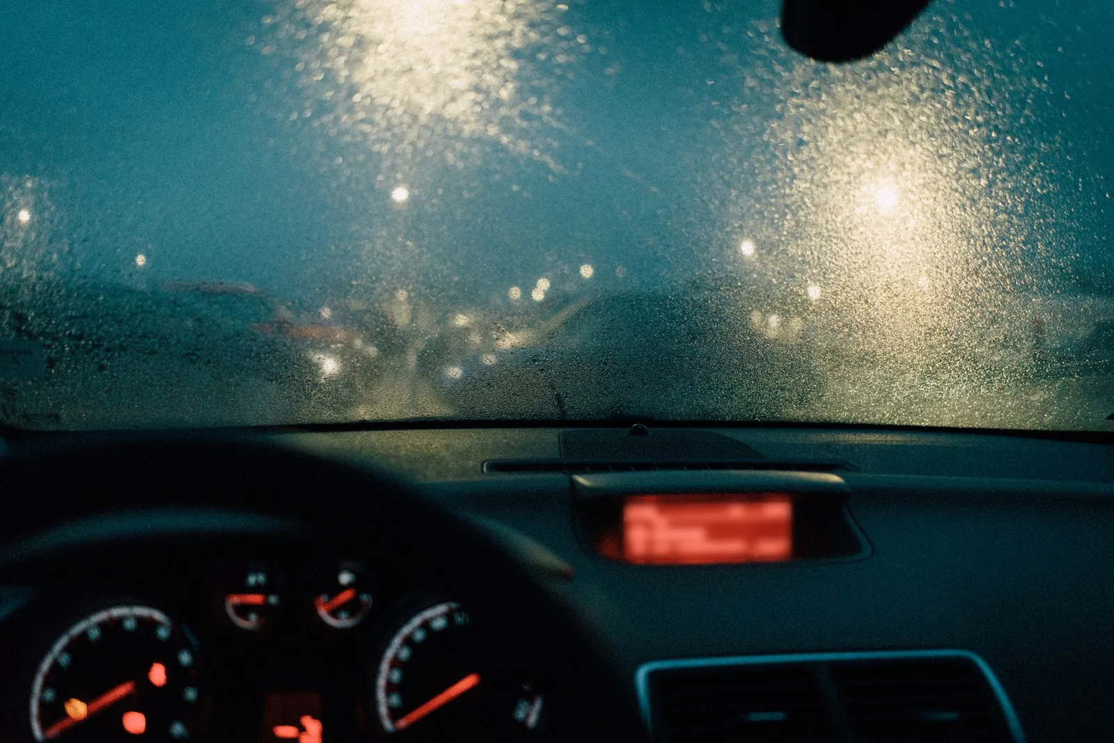 Pare-brise sous la pluie, de nuit, lumières de la ville